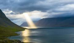 una luz traspasando unas nubes en medio de montanas