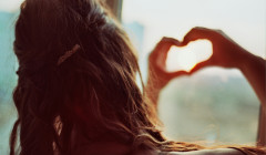 una mujer con sus manos en forma de corazon
